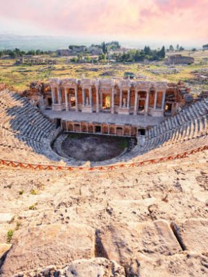 Amphitheater in ancient city of a Hierapolis under dramatic pink sky. Unesco Cultural Heritage Monument. Pamukkale, Turkey