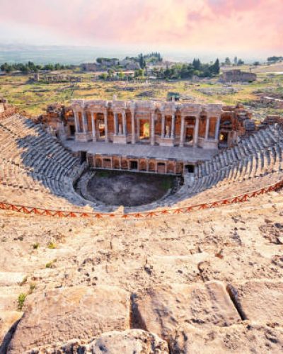 Amphitheater in ancient city of a Hierapolis under dramatic pink sky. Unesco Cultural Heritage Monument. Pamukkale, Turkey